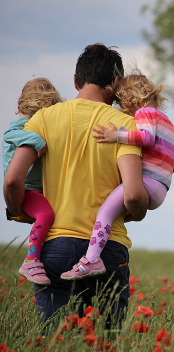 man carrying two young girls